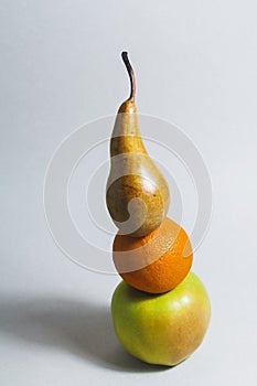 On a light background, a composition of three fruits. Apple, orange, and pear.