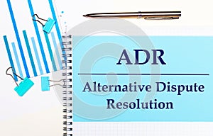 On a light background - light blue diagrams, paper clips and a sheet of paper with the text ADR Alternative Dispute Resolution.