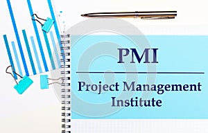 On a light background - light blue diagrams, paper clips and a sheet of paper with the text PMI Project Management Institute. View