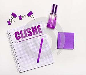 On a light background - a lilac gift, perfume, lilac business accessories and a notebook with the inscription CLICHE. Flat lay.