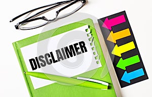 On a light background, multi-colored arrows, black glasses, a green notebook with a pen and a white card with the text DISCLAIMER