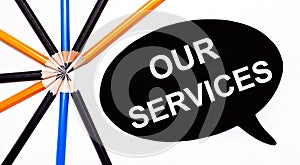 On a light background, multi-colored pencils and on a black background a white card with the text OUR SERVICES