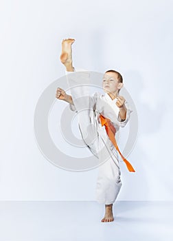 On a light background with an orange belt athlete beats a high kick leg