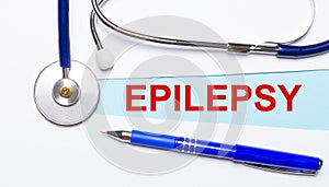 On a light background - a stethoscope, a pen and a blue strip of paper with the text EPILEPSY. Medical concept