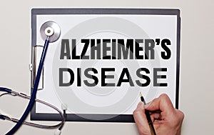 On a light background, a stethoscope and a sheet of paper, on which a man writes ALZHEIMER IS DISEASE. Medical concept