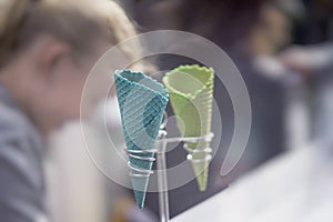 Light background with two empty bright wafer cornets for ice cream on stand, real blurry real scene. Selective focus