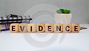 On a light background, wooden blocks with the text EVIDENCE. Close-up top view.