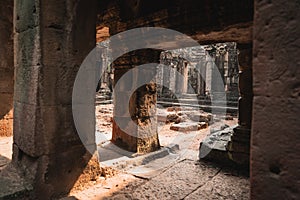 Light beams shine sharply into the the entryway of these ancient cambodian ruins photo