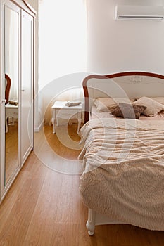 Light bedclothes on bed in cozy bedroom with mirror