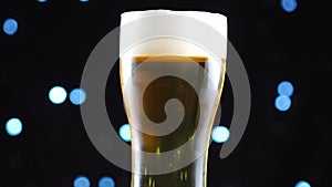 Light Beer close-up. Pint of cold light beer isolated on matte black background, rotation