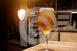 Light beer in a glass, interior pub on the background.