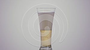 Light beer inside a long transparent glass. Action. Close up of beer alcoholic drink with a lot of foam isolated on