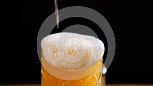 Light beer is pouring into glass. IPA. Cold Light Beer in a glass with water drops. Craft Beer forming foam close up.