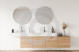 Light beige bathroom wall with original vanity and round mirrors