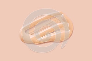 Light beige liquid makeup smear of creamy luminous blusher on beige background.