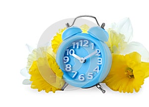 Light blue alarm clock and spring flowers on background. Time change