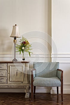 Light blue armchair and cream vintage sidebar with table lamp