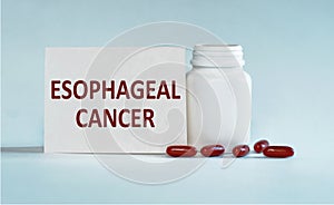 On a light blue background a card with the text ESOPHAGEAL CANCER near the white bottle pills
