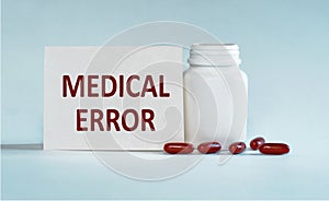 On a light blue background a card with the text MEDICAL ERROR near the white bottle pills
