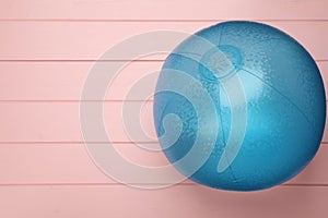 Light blue beach ball on pink wooden background, top view. Space for text