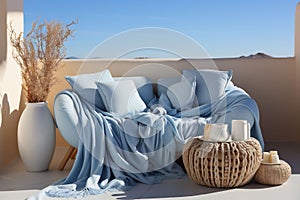 Light blue and beige terrace with sofa, blanket and pillow, and blue sky in the background. Copy space