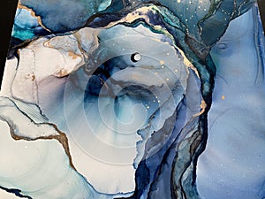 Light blue and dark blue abstract backgroud made with alcohol ink and gold pigment