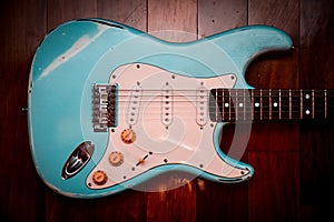 Light blue electric guitar in a brown wood background