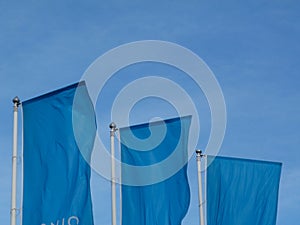 Light blue flags under blue sky on aluminum poles