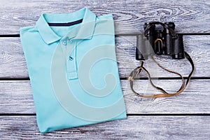 Light blue folded polo t shirt and binoculars.