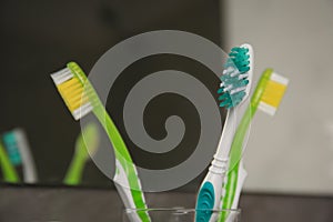 Light blue and green toothbrushes against blurred background, closeup