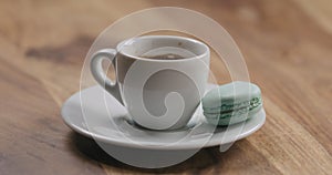 Light blue macaron on saucer with coffee cup