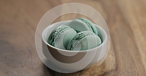 Light blue macarons in white bowl on wood table