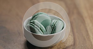 Light blue macarons in white bowl on wood table
