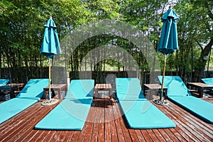 Light blue pool chairs on wooden floor in luxury hotel