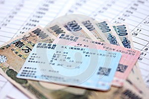 Light blue and red Japan Health Insurance cards on table with japanese yen money