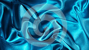 Light blue silk satin. Folds on shiny fabric surface. Beautiful teal background with space