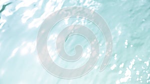 Light blue surface of water in swimming pool with gentle ripples on the surface.