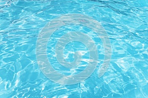 Light Blue swimming pool rippled water texture reflection. Beautiful blue water background with glare from sun