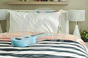 Light blue ukulele on striped bedding