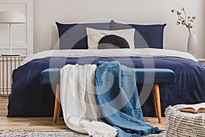 Light blue and white blanket on bench in elegant bedroom