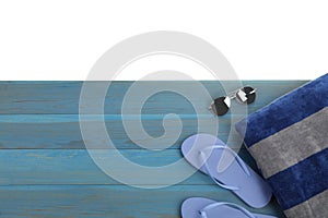 Light blue wooden surface with beach towel, flip flops and sunglasses on white background, top view. Space for text