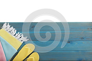 Light blue wooden surface with beach towel and flip flops on white background, top view. Space for text