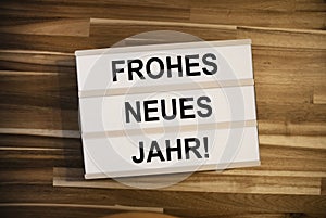 Light box  or lightbox with the german words for happy new year - frohes neues jahr on a wooden table background