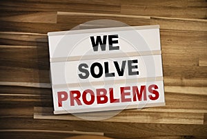 Light box or lightbox with message We Solve Problems on a wooden table background