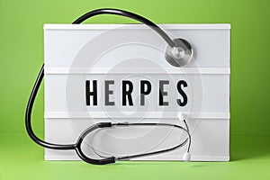 Light box with word Herpes and stethoscope on green background