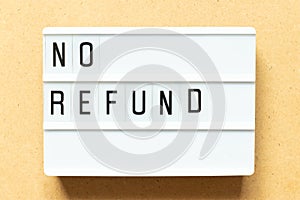 Light box with word no refund on wood background