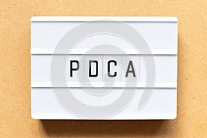 Light box with word PDCA business abbreviation of plan do check act on wood background