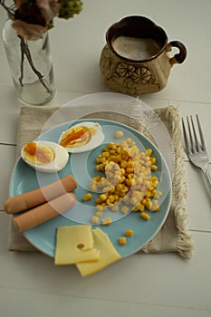 Light breakfast of corn, cheese, sausages and eggs with a sauce