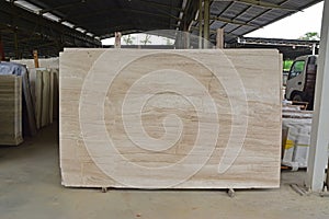 Light brown marble slab displayed within a large warehouse photo