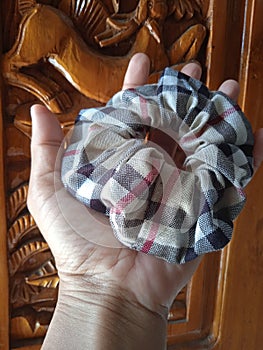 Light brown pattern scrunchie with balinese carved wood as background